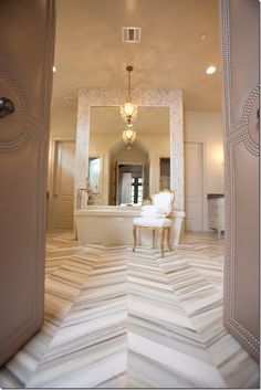 an open door leading to a bathroom with a tub and chandelier in it