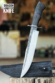 a large knife sitting on top of a piece of wood