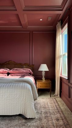 a bed sitting in a bedroom next to a window with a lamp on top of it