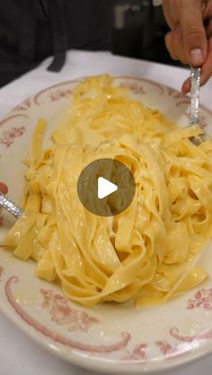 a plate with pasta on it and someone holding a fork over the top of it