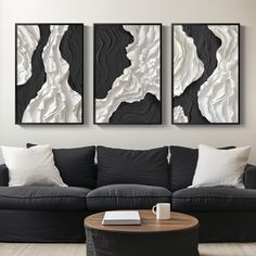 three black and white paintings hanging on the wall above a couch in a living room