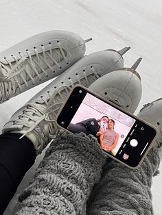 someone is taking a selfie with their cell phone in the snow while wearing gray sneakers