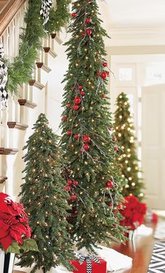 christmas trees are decorated with red and green ornaments on the banisters in this foyer