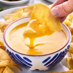 a hand dipping tortilla chips into a bowl of quesadilla soup