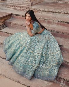 a woman in a blue dress sitting on some steps with her hand near her face