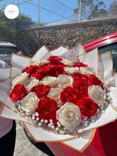 a bouquet of red and white roses in front of a car