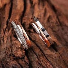 two wedding rings sitting on top of a wooden tree trunk with diamonds in the middle