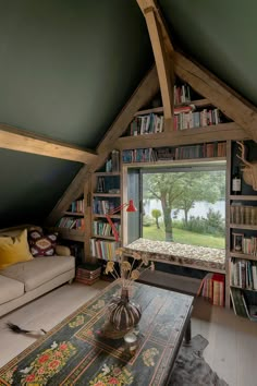 a living room filled with furniture and a book shelf next to a window covered in books