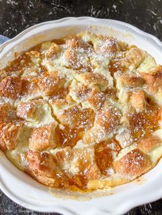 a pie with powdered sugar on top sits in a white casserole dish