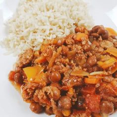 a white plate topped with rice and chili next to meat covered in sauce on top of it