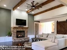 a living room with couches and a tv mounted on the wall in front of a fireplace