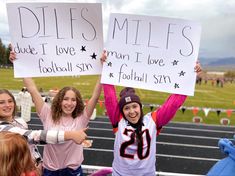 two girls holding up signs at a football game