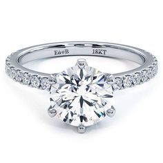 a round brilliant cut diamond engagement ring with pave set diamonds on the band and side stones