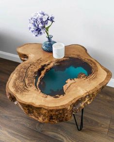 a table made out of a tree trunk with blue water in the center and flowers on top