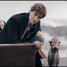 a man in a suit and tie sitting next to a stuffed animal