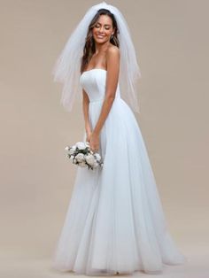 a woman in a white wedding dress holding a bouquet and posing for the camera with her veil over her head