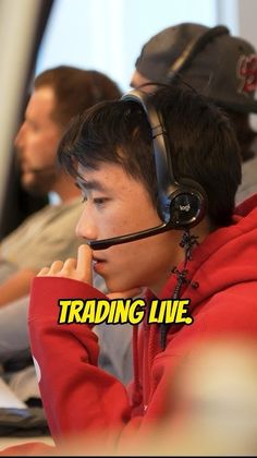 a young man wearing headphones while sitting in front of a computer screen with the words trading live on it