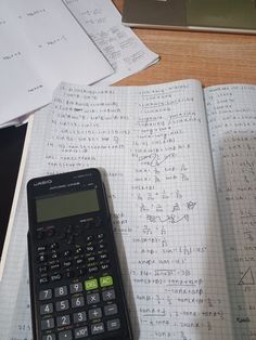 a calculator sitting on top of an open notebook