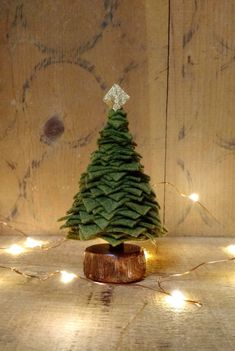 a small green christmas tree sitting on top of a wooden table