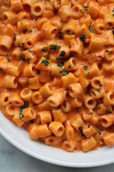 a white bowl filled with macaroni and cheese on top of a marble table