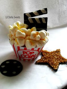 a popcorn bucket filled with marshmallows next to a star shaped cookie