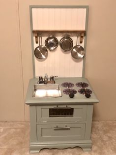 a small stove with pots and pans mounted to the wall