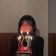 a woman covering her face with candles