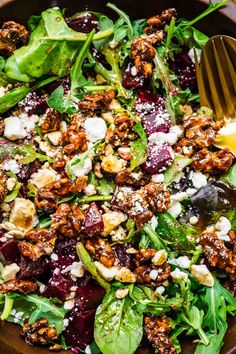 a salad with spinach, feta cheese and walnuts in a brown bowl