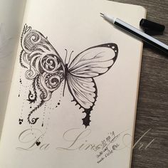 a drawing of a butterfly on top of a book next to a pen and paper