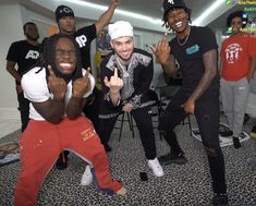 the young men are posing for a photo in front of some chairs and one man is pointing