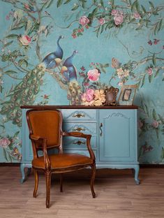 a chair sitting in front of a blue cabinet with flowers and birds painted on it