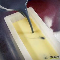 a spoon pouring yellow liquid into a container