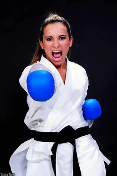 a woman in a white kimono and blue boxing gloves with her mouth wide open