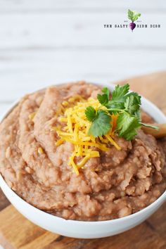 a white bowl filled with oatmeal topped with cheese and cilantro