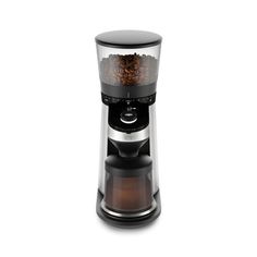 a coffee grinder filled with lots of coffee beans on top of a white surface