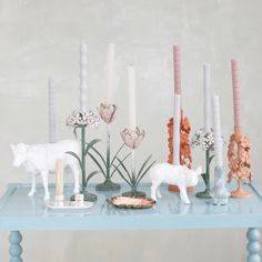 a table topped with candles and figurines on top of blue countertop next to flowers