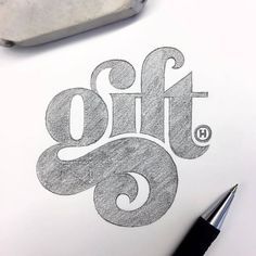 a drawing of the word gift on paper next to a pen and inking tool