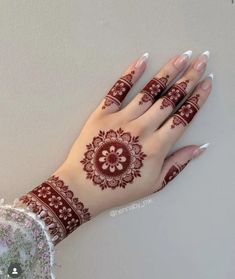 a woman's hand with henna tattoos on it