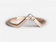 a gold ring with three diamonds on it's sides, sitting on a white surface