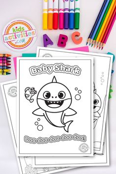 baby shark coloring pages with crayons, markers and pencils on the table