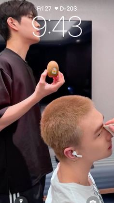 a young man is getting his hair cut by another person with an earpiece in front of him