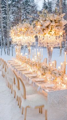 a long table set up with white flowers and candles in the snow for a winter wedding