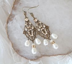 These antique gold bridal earrings are created with highly detailed luxurious antique brass filigree drops in which I placed Swarovski golden shadow crystals, Swarovski ivory pearls and Swarovski rondelles. These dangle dramatically 3-1/2 inches from top of ear wire to bottom of center pearl drop. This is an original design by © Treasures by Agnes PLEASE ALLOW 10 DAYSFOR COMPLETION. All pieces come beautifully gift wrapped. Custom orders welcome. ALL ORDERS ARE SHIPPED VIA USPS FIRST CLASS WITH Victorian Wedding Earrings With Antique Finish, Vintage Brass Chandelier Earrings For Wedding, Antique Gold Jeweled Jewelry For Weddings, Antique Finish Bronze Wedding Earrings, Teardrop Filigree Chandelier Earrings For Wedding, Brass Dangle Bridal Earrings, Wedding Pearl Drop Brass Earrings, Antique Finish Drop Earrings For Wedding, Wedding Pearl Drop Earrings In Brass