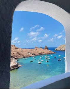 boats are floating in the blue water near an arch that looks out into the ocean