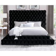 a bed with black velvet headboard and white linens on it, in a bedroom