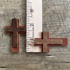 two wooden crosses are next to a measuring ruler on a piece of wood that has been cut in half