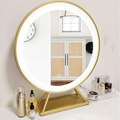 a round mirror sitting on top of a table next to a shelf with makeup and other items