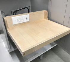 a wooden table with an electrical outlet on the top and power strip attached to it