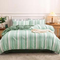 a green and white striped comforter set on a bed in a room with two lamps