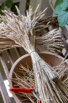 two buckets filled with dried grass and some red handled brooms sitting on top of each other